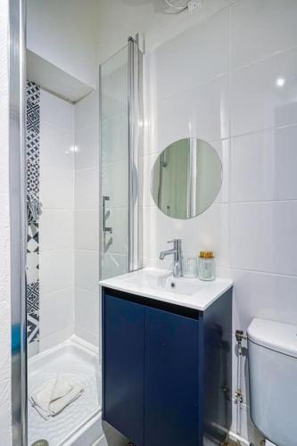 une salle de bain blanche avec un lavabo et une douche dans l'établissement Appartement équipé quartier Montparnasse - II, à Paris