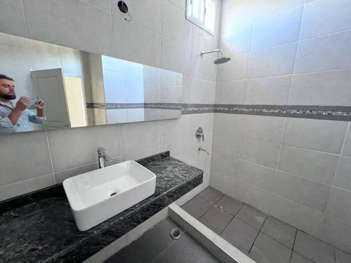 Ein Mann fotografiert ein Badezimmer mit Waschbecken. in der Unterkunft quincho el atardecer in Santa Lucía