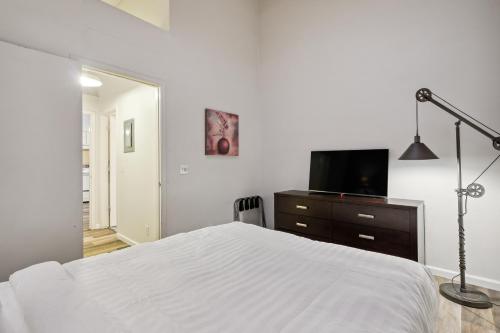 a white bedroom with a bed and a television at THE CARRICK in Bisbee