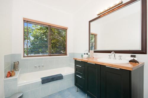a bathroom with a white tub and a sink and a bath tubermott at Byron Bay Accom - Alkira 1/32 Alcorn St in Suffolk Park