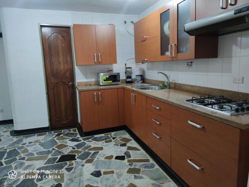 eine Küche mit Holzschränken, einer Spüle und einem Herd in der Unterkunft Alojamiento cómodo en el centro de la ciudad. in Pereira