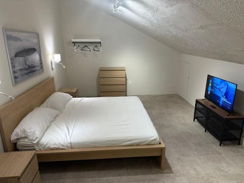 a bedroom with a white bed and a television at Departamentos Flamboyant in Acapulco