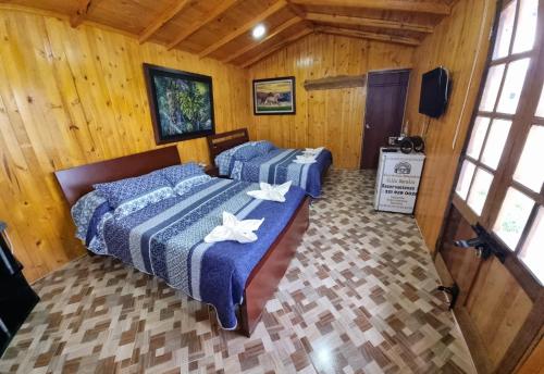 two beds in a room with wooden walls and windows at Alojamiento Villa Doralis in Guatavita