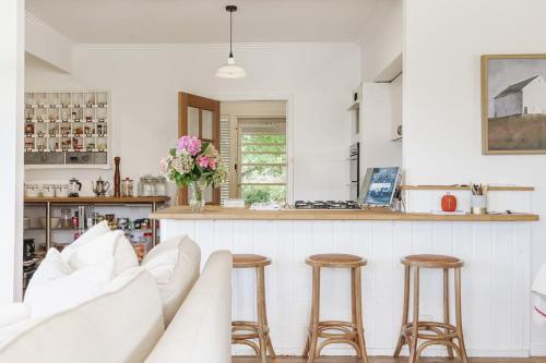 a kitchen with white furniture and a counter with stools at Serenity in Red Hill - Winery Bliss & Coastal Beauty in Red Hill South