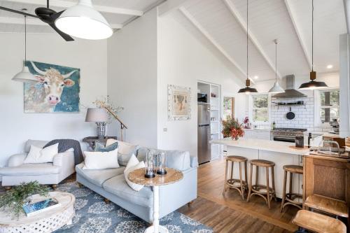 a living room and kitchen with a couch and a table at Cottage Enchantment - A Blooming Garden Getaway in Red Hill South