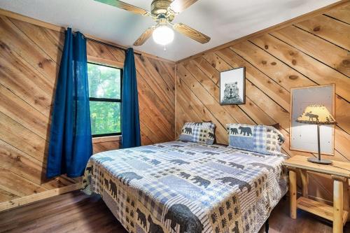 a bedroom with wooden walls and a bed with blue curtains at Couples Getaway Hot Tub & Mountain View in Sevierville