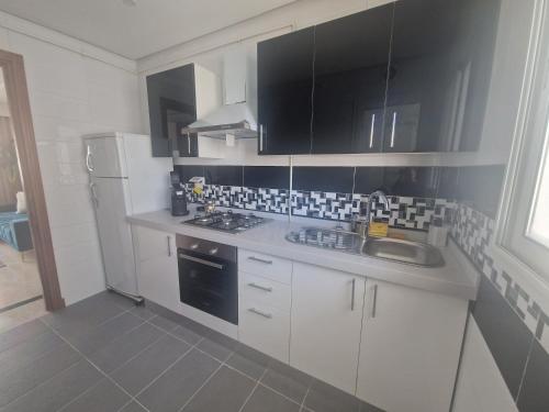 a kitchen with white cabinets and a sink and a refrigerator at Appartement proche de la plage in Bizerte