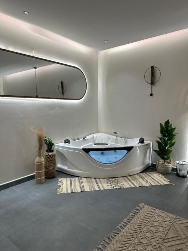 a white bathroom with a tub in a room at شاليه أوڤال Oval Chalet in Al Jubail
