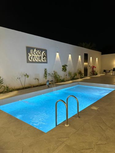 a large blue swimming pool in front of a building at شاليه أوڤال Oval Chalet in Al Jubail