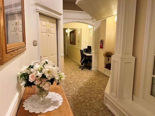 a hallway with a vase of flowers on a table at Best Western Grandma's Feather Bed in Mendenhaven