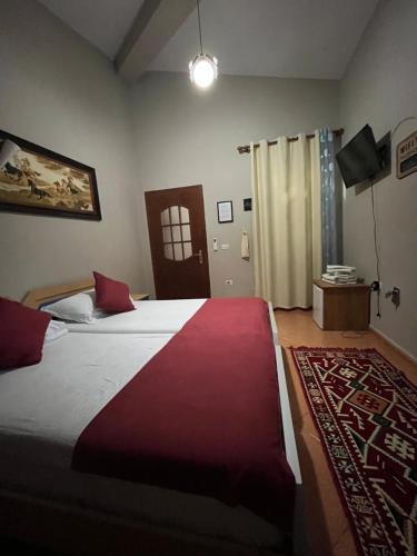 a bedroom with a large bed with a red blanket at ROOMS EMILIANO Castle of Kruja in Krujë