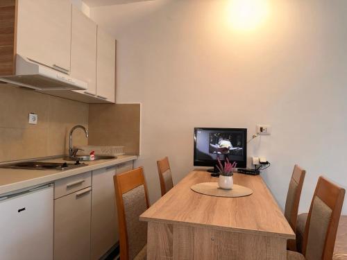 eine Küche mit einem Holztisch mit Stühlen und einem TV in der Unterkunft Apartman Masa Kopaonik in Kopaonik