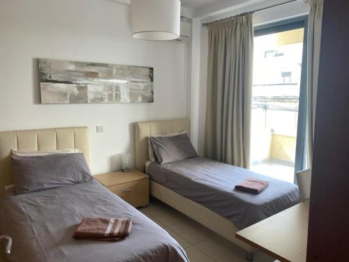 a bedroom with two beds and a window with a view at Spinola Residence St Julians in St Julian's