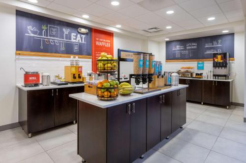a cafeteria with a counter with fruit in baskets on it at Hampton Inn Milford in Milford
