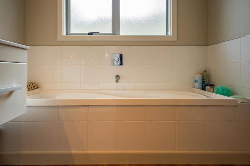 a bath tub in a bathroom with a window at Bach 32 - Taupo Holiday Home in Taupo
