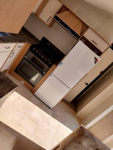 an overhead view of a kitchen with white cabinets at Private holiday home on Lyons Winkups holiday park, North Wales. in Kinmel Bay