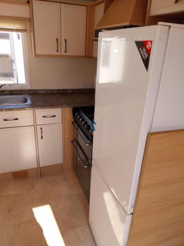 a kitchen with a white refrigerator and a stove at Private holiday home on Lyons Winkups holiday park, North Wales. in Kinmel Bay