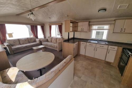 a kitchen and living room with a table and a couch at Private holiday home on Lyons Winkups holiday park, North Wales. in Kinmel Bay