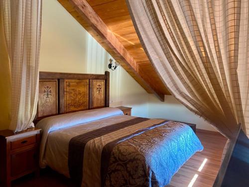 a bedroom with a bed with a wooden headboard and curtains at Los Reales in Carrizo de la Ribera