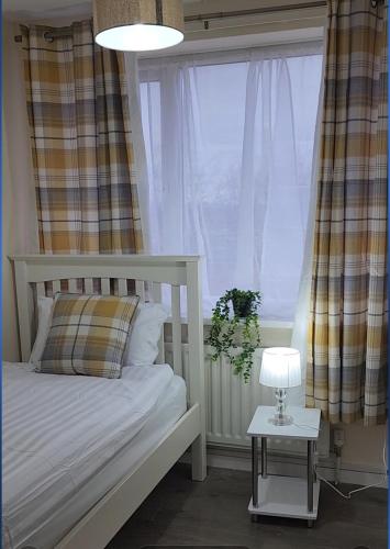 a bedroom with a bed with a lamp and a window at Exquisite Stays Free parking, fast WiFi, close to city centre in Kenton