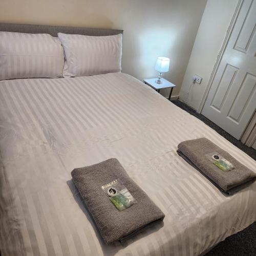 a bed with two towels on top of it at Exquisite Stays Free parking, fast WiFi, close to city centre in Kenton