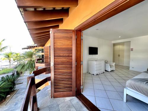 a room with a balcony with a bed and a television at Luna Hotel Boutique - Frente à Praia in Guarujá