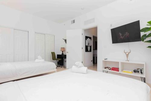 a white bedroom with two beds and a tv at 1-BR Apartment Downtown Miami - Heart of Wynwood and Midtown in Miami