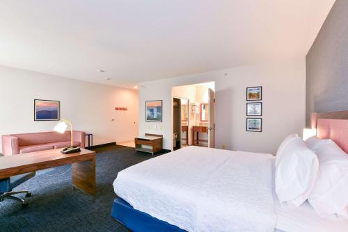 ピッツバーグにあるHampton Inn & Suites Pittsburgのベッドとデスクが備わるホテルルームです。