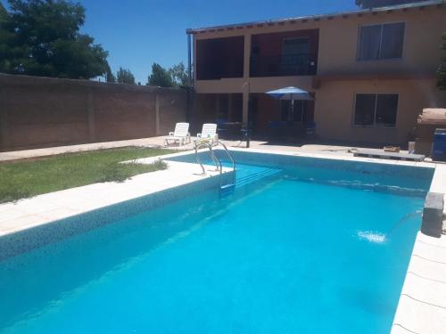 a swimming pool with two chairs and a house at Departamentos San Benito in Malargüe