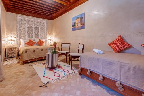 1 dormitorio con 2 camas, mesa y sillas en Riad Amalia, en Marrakech