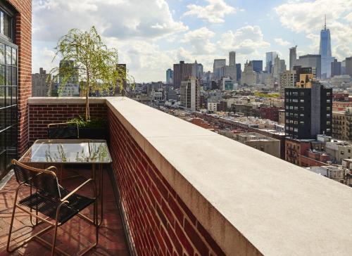 a balcony with a glass table and a view of a city at The Ludlow Hotel in New York