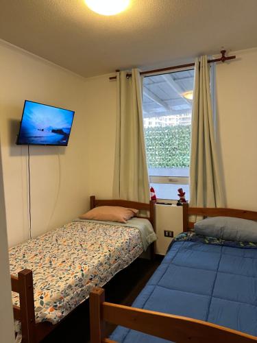 a bedroom with two beds and a tv on the wall at Departamento Playa Brava Iquique 3D 2B in Iquique