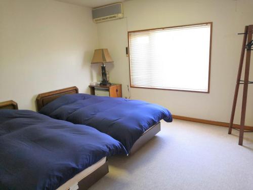 2 camas azules en una habitación con ventana en Villa Yukar with Hot Spring 高級感あふれる温泉付別荘 ヴィラユカラ　　, en Shiraoi