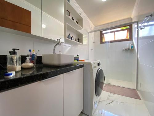 a white kitchen with a sink and a washing machine at Loft classe A in Santa Cruz do Sul