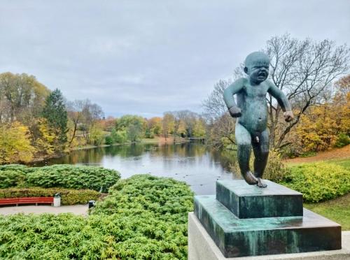 a statue of a boy standing in front of a lake at Frogner Park Penthouse Terrace in Oslo