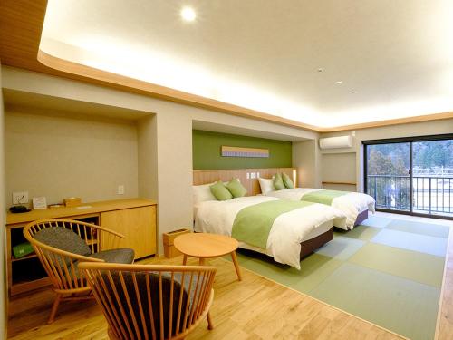 um quarto com 2 camas, uma mesa e cadeiras em Yunogo Grand Hotel em Mimasaka