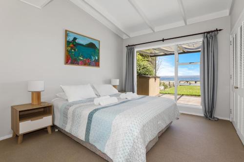 a bedroom with a bed and a large window at Hannah's Bay Lakefront in Rotorua