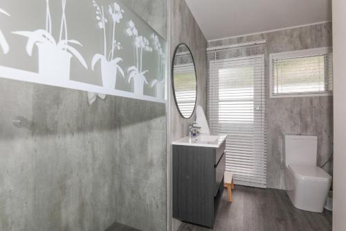 a bathroom with a sink and a toilet and a mirror at Hannah's Bay Lakefront in Rotorua