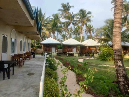 - une terrasse avec des tables, des chaises et des palmiers dans l'établissement JMJ/GOD THE FATHER HOME STAY, à Caridad