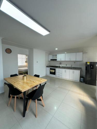 a large white kitchen with a wooden table and chairs at Apto estudio con parqueadero y wifi. in Yopal