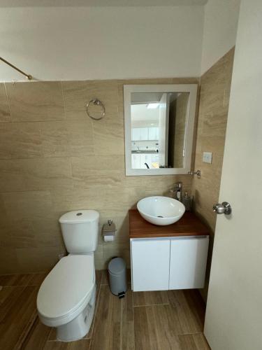 uma casa de banho com um WC, um lavatório e um espelho. em Apto estudio con parqueadero y wifi. em Yopal