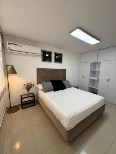 um quarto com uma grande cama branca e um candeeiro em Apto estudio con parqueadero y wifi. em Yopal