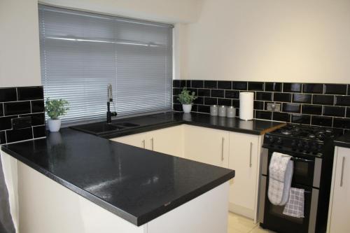 a kitchen with a black counter top and a sink at Exquisite Stays Free parking, fast WiFi, close to city centre in Kenton