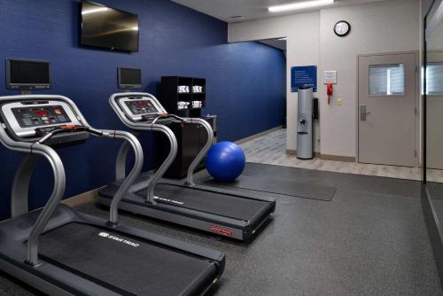 a gym with two cardio machines and a blue wall at Hampton Inn Kansas City Northeast in Kansas City
