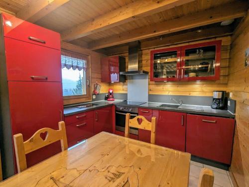 une cuisine avec des placards rouges et une table en bois dans l'établissement Chalet confortable à Cleurie avec WIFI, cheminée et terrasse - FR-1-589-71, à Cleurie