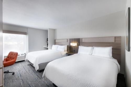 a hotel room with two beds and a chair at Holiday Inn Express Atlanta West - Theme Park Area by IHG in Lithia Springs