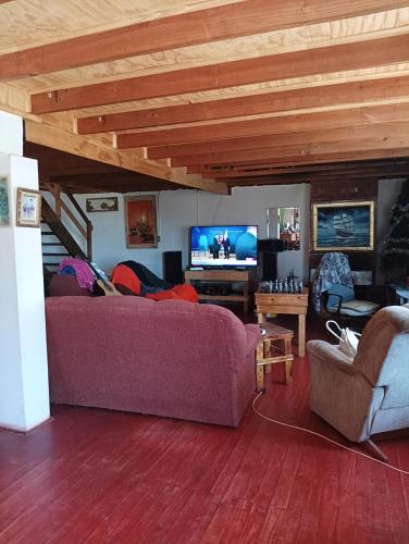 uma sala de estar com um sofá e uma televisão em Don Fernando em El Quisco