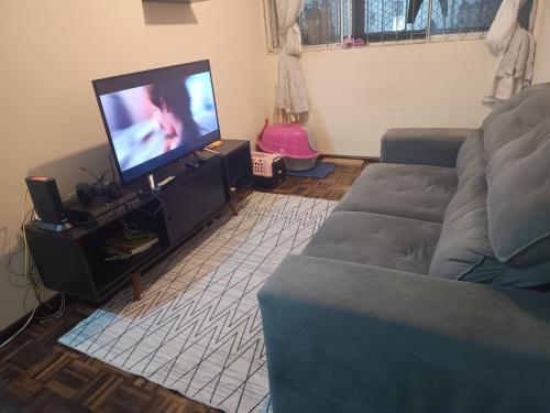 sala de estar con sofá y TV de pantalla plana en Axel costa en Curitiba