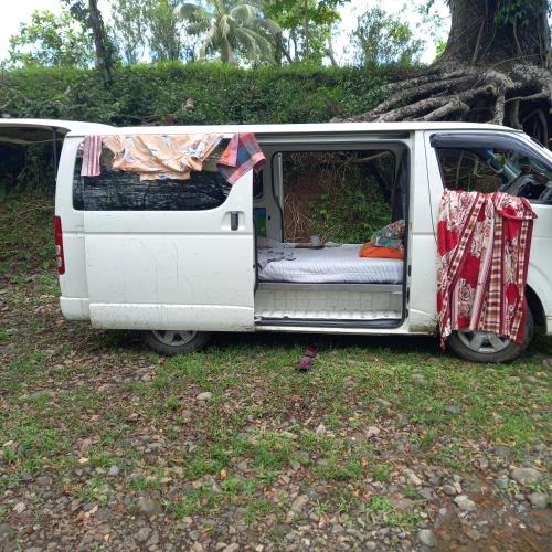 una furgoneta blanca estacionada en el césped con la puerta abierta en Turtle Campervans Fiji, en Korotogo
