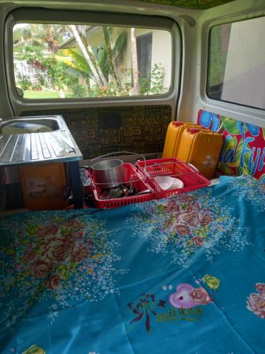 Una furgoneta con una cama con una mesa con comida y una bandeja en Turtle Campervans Fiji, en Korotogo
